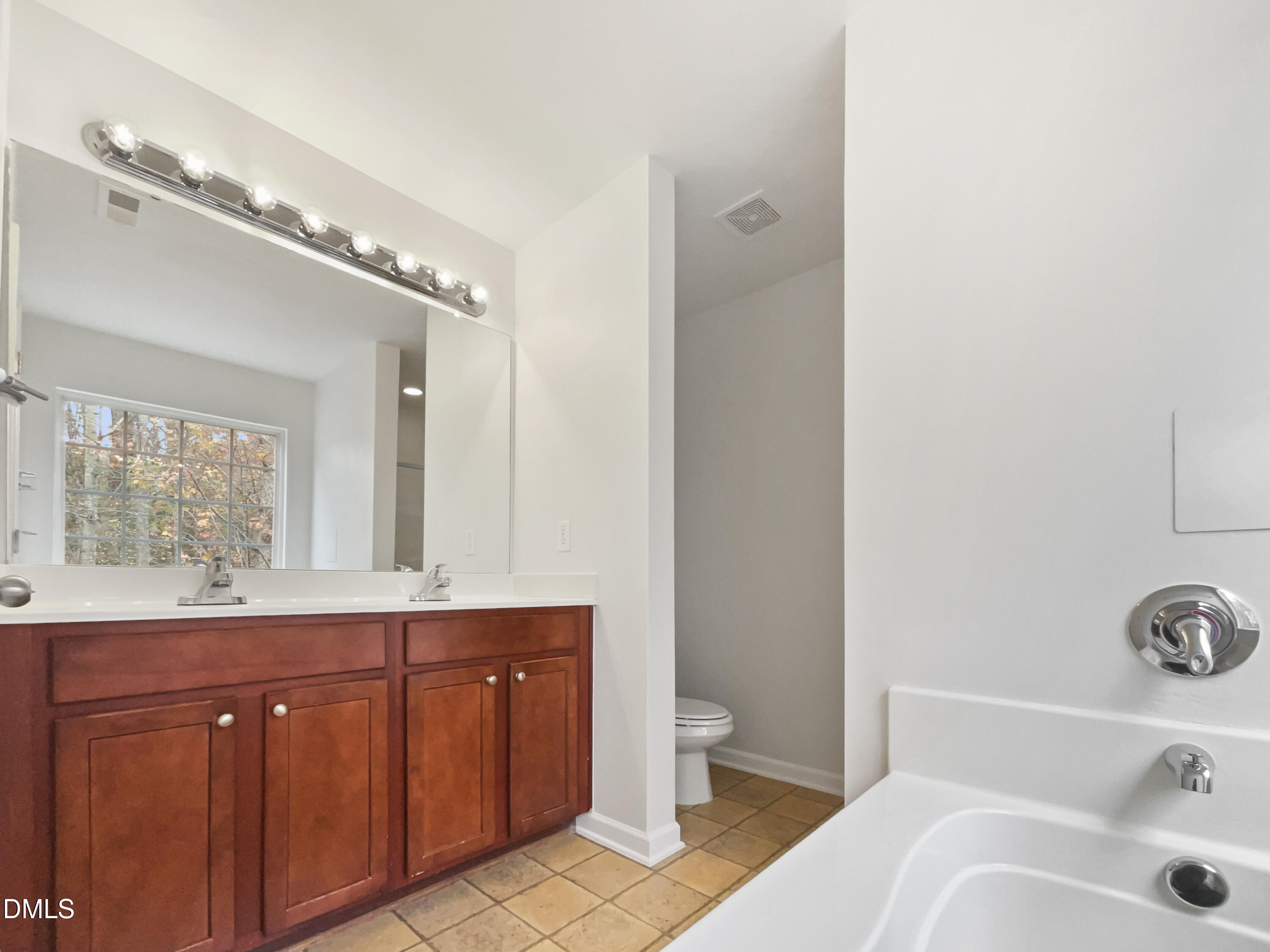 5512 Quitman Trail Raleigh, NC 27610 - Photo 15 of 18 a spacious bathroom with a double vanity sink a mirror and a toilet