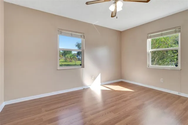 a view of an empty room with window and wooden floor