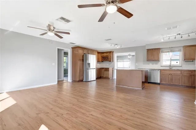 a view of a kitchen with a sink dishwasher a kitchen view with wooden floor and cabinets