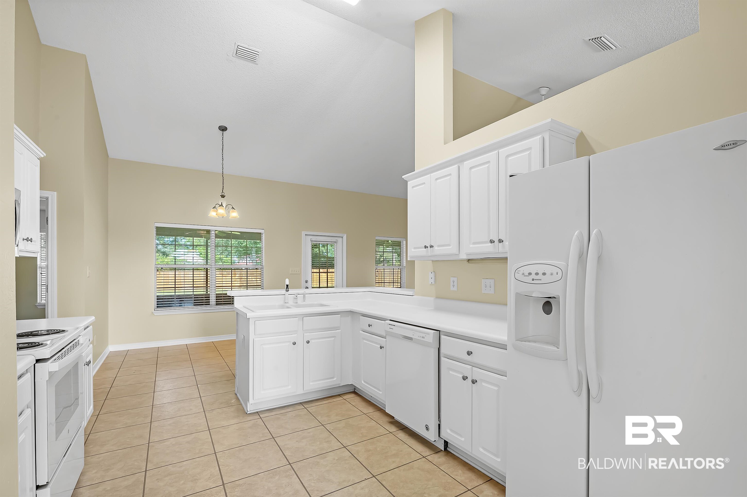12443 Venice Boulevard Foley, AL 36535 - Photo 33 of 59 Kitchen featuring kitchen peninsula, decorative light fixtures, white appliances, and white cabinetry