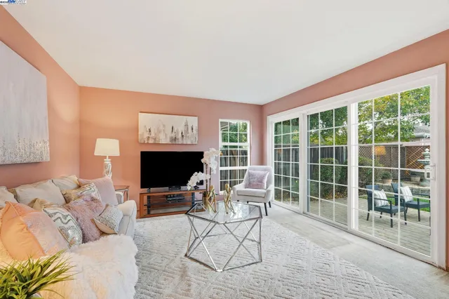 a living room with furniture a floor to ceiling window and a flat screen tv
