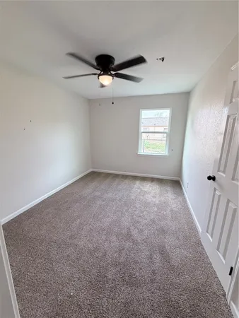 an empty room with a ceiling fan and window