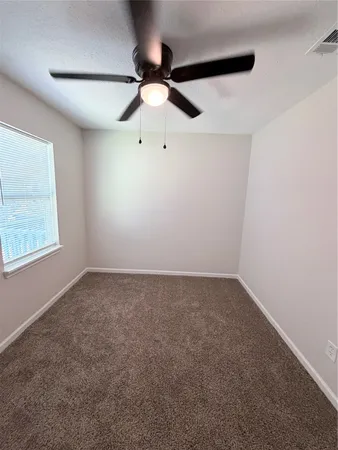 an empty room with a window and a fan