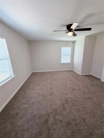 en empty room with windows and ceiling fan