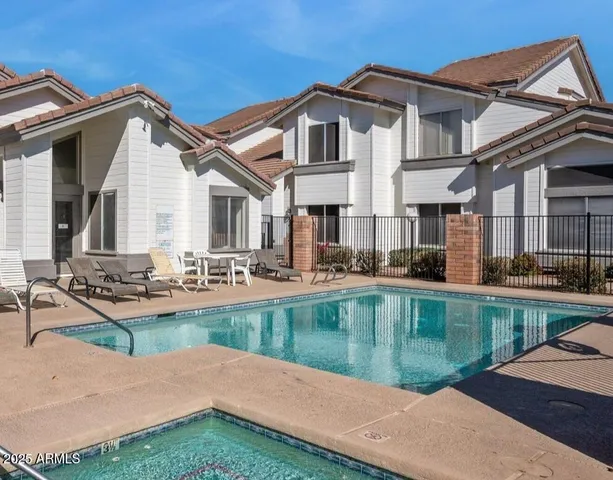 a view of a house with pool lawn chairs and a dining table under an umbrella