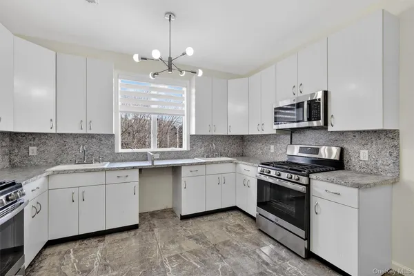 a kitchen with stainless steel appliances granite countertop a stove a sink and a microwave