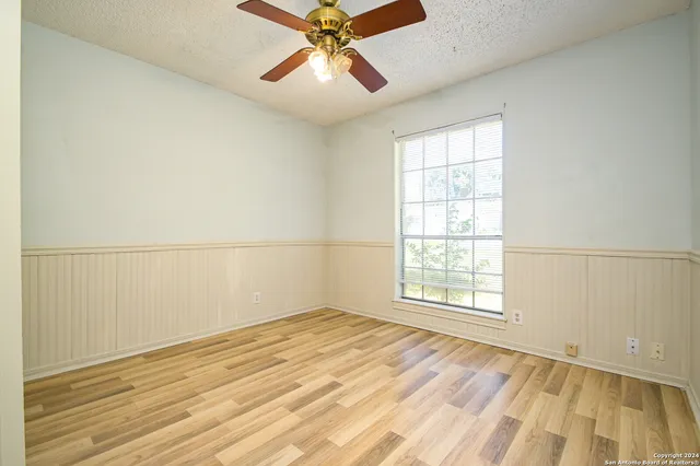an empty room with wooden floor fan and windows