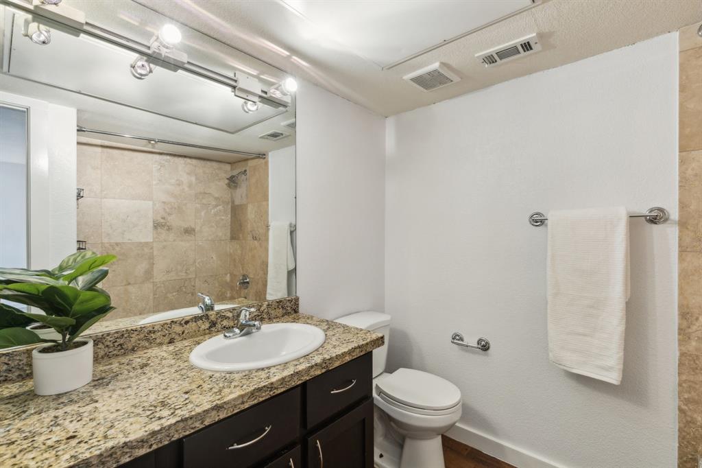 4777 Cedar Springs Road, Unit 6N Dallas, TX 75219 - Photo 21 of 24 a bathroom with a granite countertop sink a toilet a mirror and shower