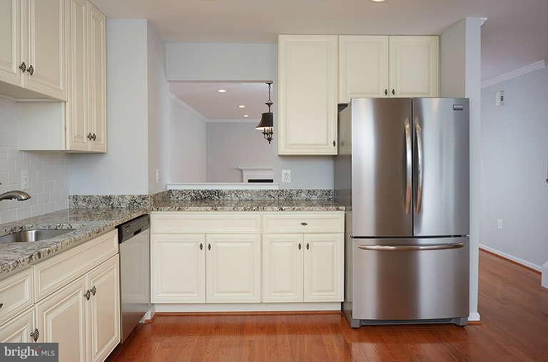 a kitchen with granite countertop stainless steel appliances a refrigerator a sink and cabinets