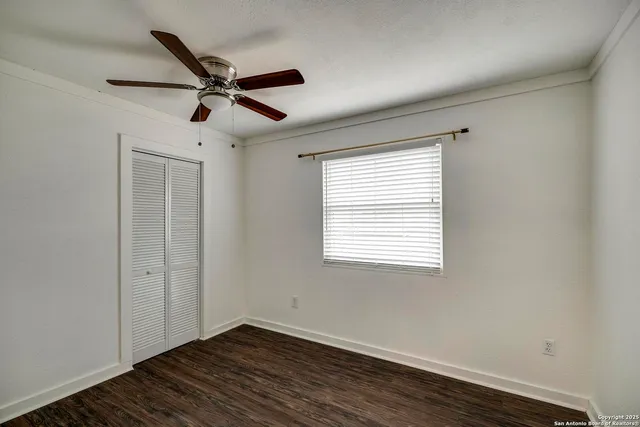 a view of empty room with wooden floor and fan