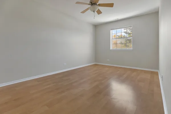 an empty room with wooden floor fan and windows