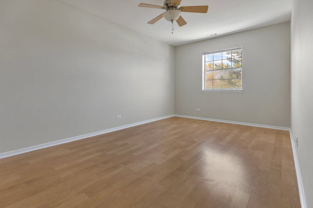 86 Gant Circle, Unit F Streamwood, IL 60107 - Photo 8 of 20 an empty room with wooden floor fan and windows