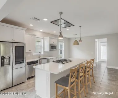 a kitchen with stainless steel appliances granite countertop a sink a stove a refrigerator and island with wooden floor