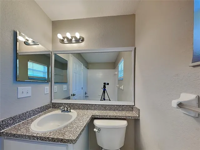 a bathroom with a granite countertop sink a toilet and mirror