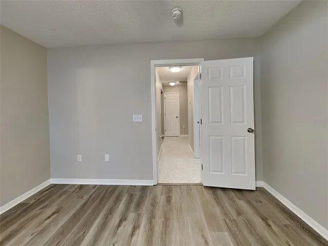 a view of an empty room with wooden floor and closet