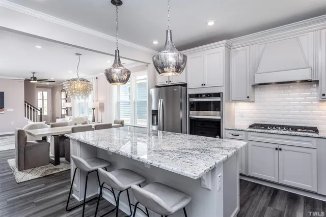 a kitchen with stainless steel appliances granite countertop a stove a refrigerator a kitchen island a sink and chairs