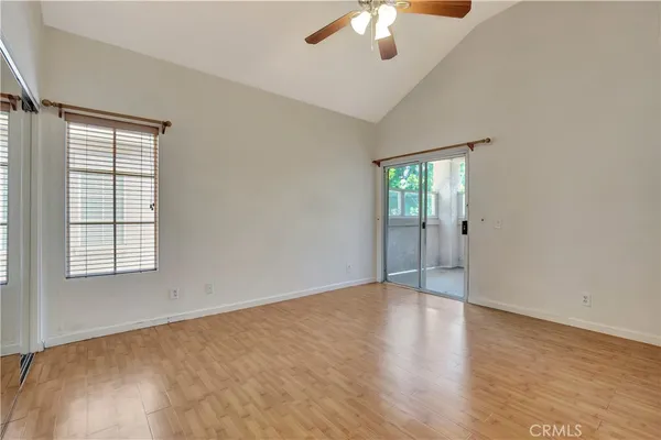 an empty room with chandelier fan and windows