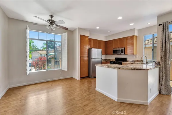 a kitchen with stainless steel appliances granite countertop a refrigerator a stove top oven a sink and dishwasher with wooden floor