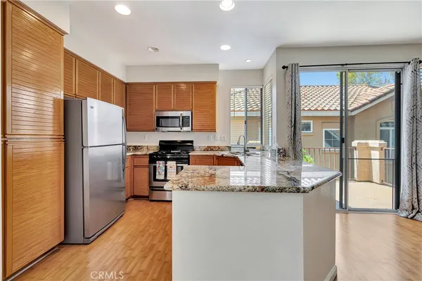 a kitchen with stainless steel appliances granite countertop a refrigerator a stove and a sink with wooden floor
