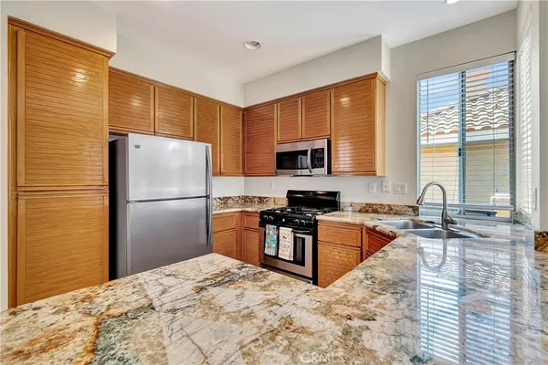a kitchen with stainless steel appliances granite countertop a refrigerator stove microwave and sink
