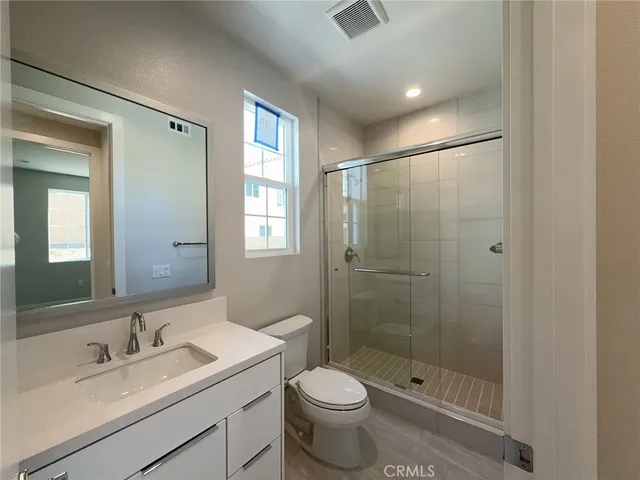 a bathroom with a shower sink vanity mirror and toilet