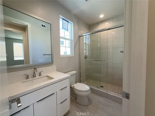 a bathroom with a shower sink vanity mirror and toilet
