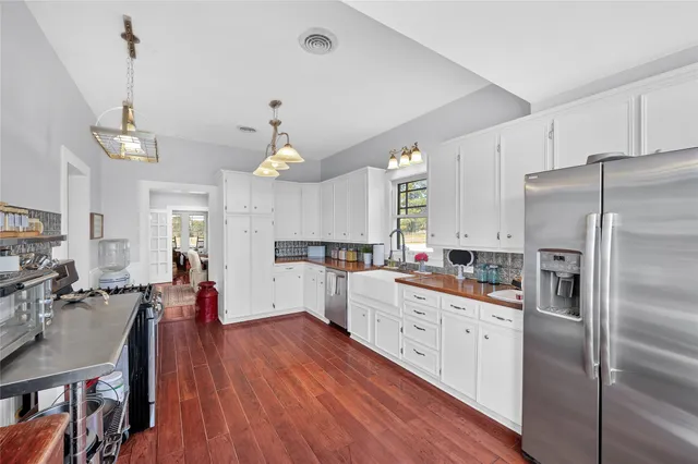 a large kitchen with cabinets chairs and stainless steel appliances