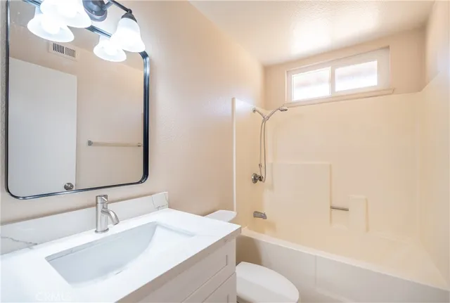 a bathroom with a sink vanity granite tub toilet and a mirror