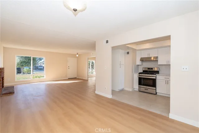 a view of empty room with kitchen and window