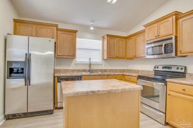 a kitchen with stainless steel appliances granite countertop a refrigerator a stove a sink and a microwave