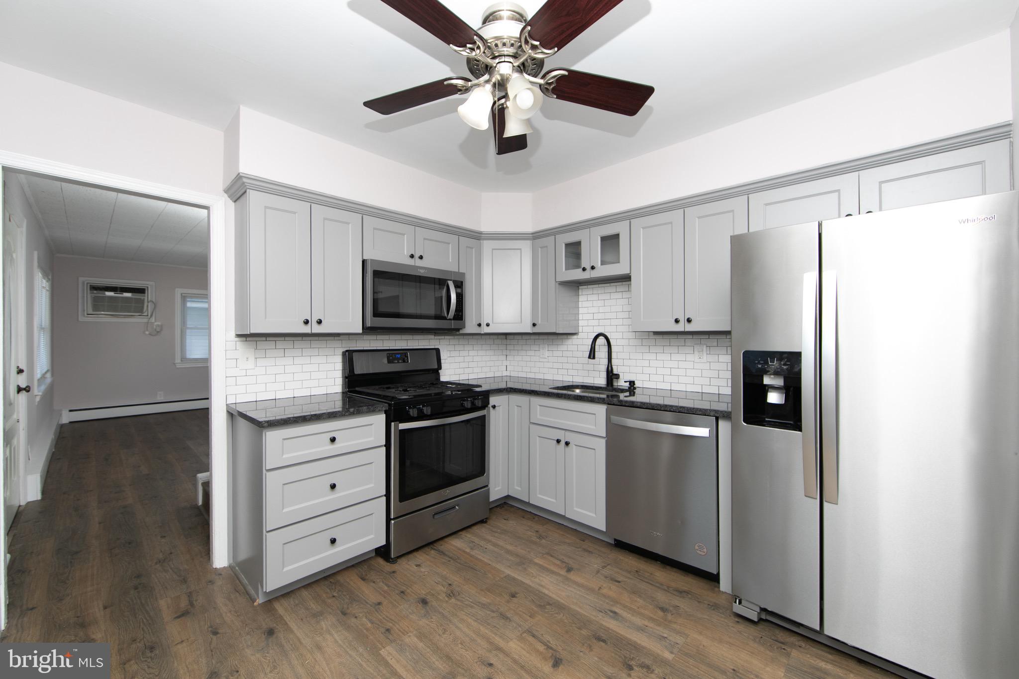 553 Maple Avenue Audubon, NJ 08106 - Photo 6 of 49 a kitchen with stainless steel appliances granite countertop a refrigerator a stove top oven a sink and dishwasher with wooden floor
