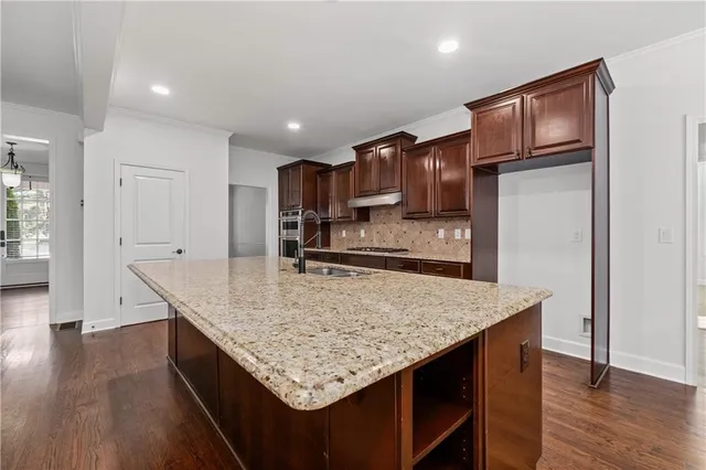 a kitchen with kitchen island granite countertop wooden cabinets a refrigerator and wooden floor