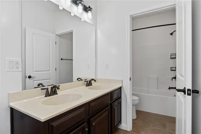 a bathroom with a sink a toilet a mirror and shower