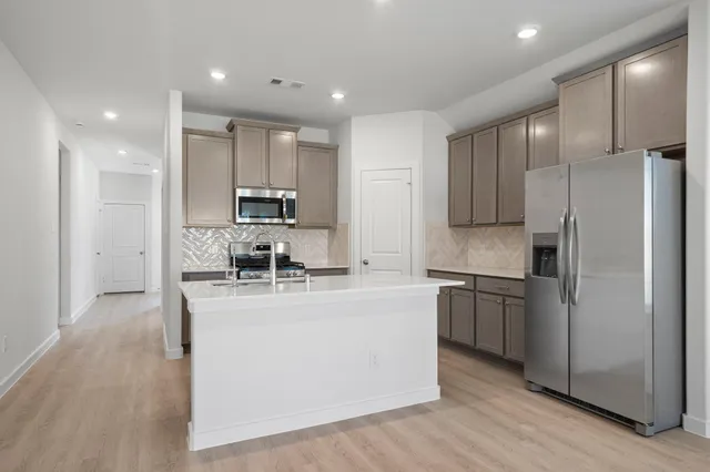 a kitchen with kitchen island a counter top space a refrigerator and cabinets