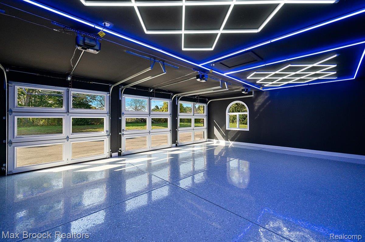 4597 Clarkston Road Clarkston, MI 48348 - Photo 59 of 74 Three glass-paneled garage doors, arched window, dark-painted walls, finished flooring, and ceiling with integrated lighting