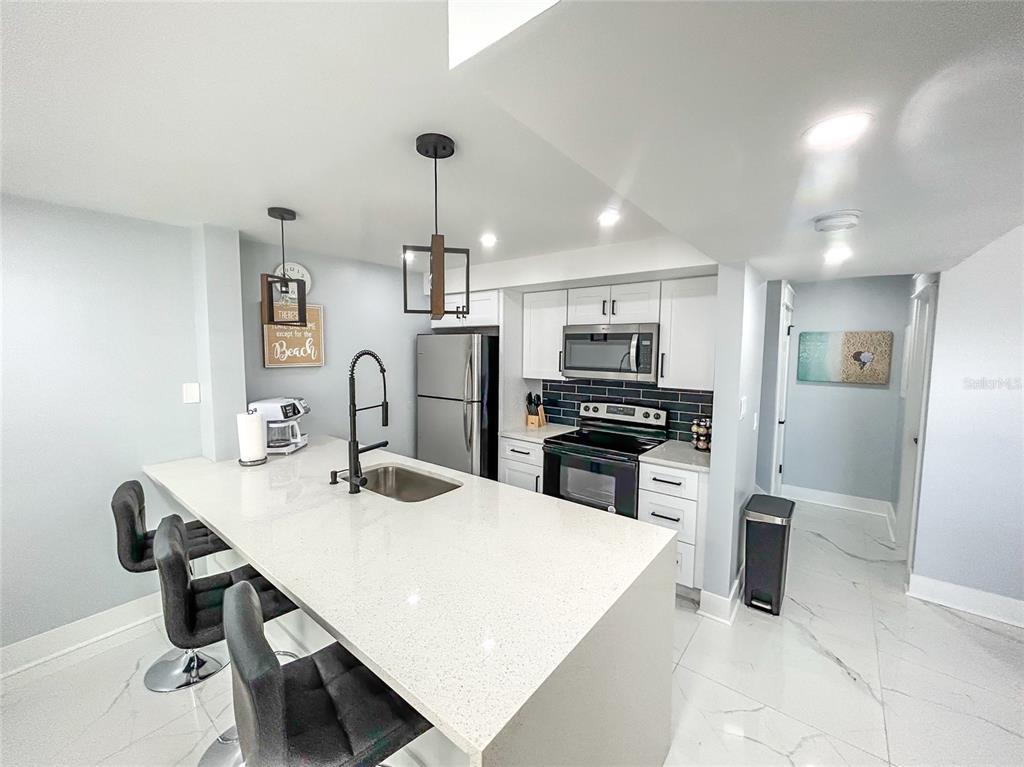 315 Medallion Boulevard, Unit F Madeira Beach, FL 33708 - Photo 3 of 18 a kitchen with refrigerator cabinets and chairs