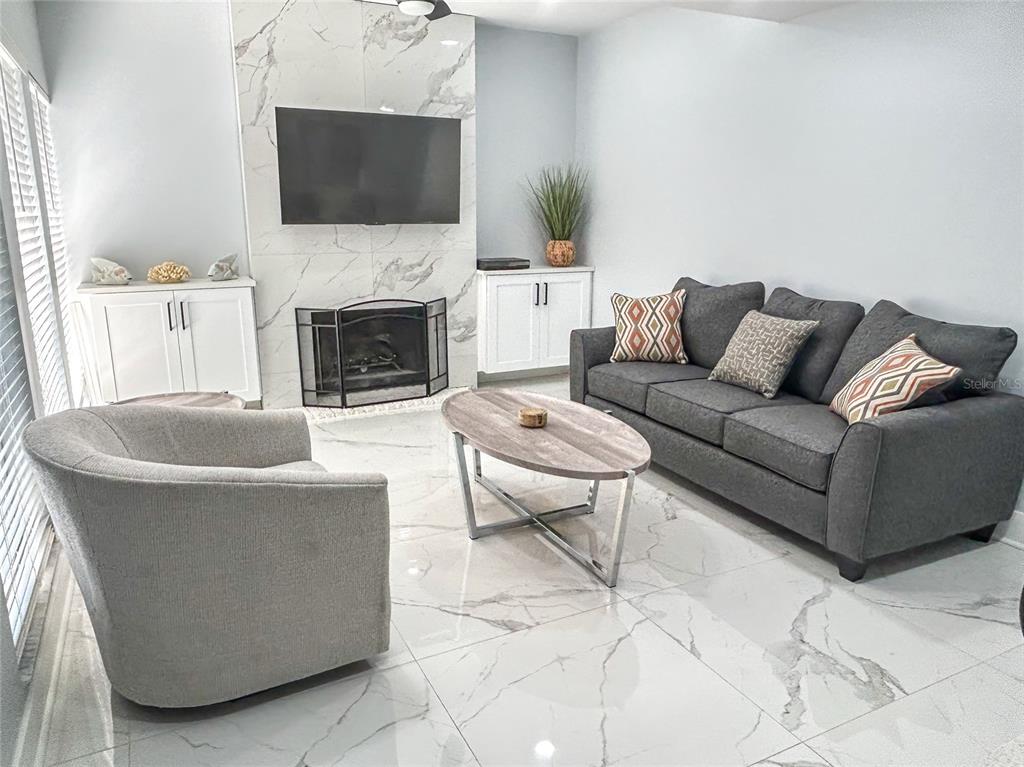 315 Medallion Boulevard, Unit F Madeira Beach, FL 33708 - Photo 6 of 18 a living room with furniture a flat screen tv and a fireplace