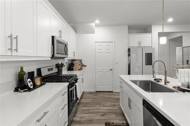 a kitchen with a sink dishwasher a stove and a refrigerator with wooden floor