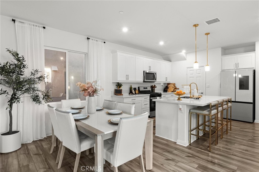 352 Alice Avenue Rialto, CA 92376 - Photo 16 of 41 a kitchen with a table chairs stove and white cabinets