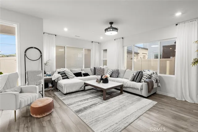 a living room with furniture kitchen view and a wooden floor