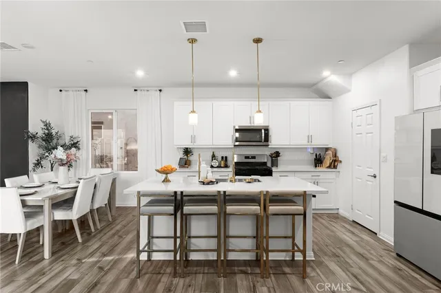 a kitchen with stainless steel appliances a table chairs refrigerator and microwave