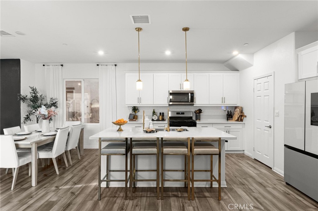 352 Alice Avenue Rialto, CA 92376 - Photo 10 of 41 a kitchen with stainless steel appliances a table chairs refrigerator and microwave