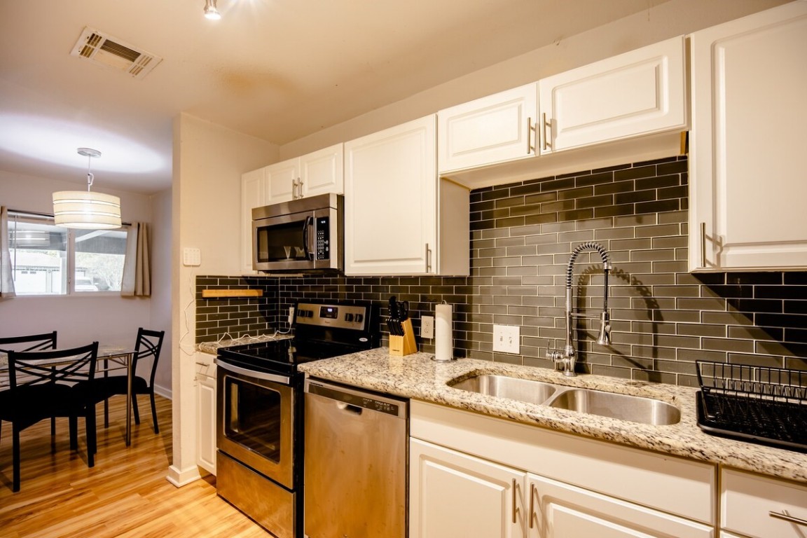 2603 Parker Lane, Unit B Austin, TX 78741 - Photo 13 of 40 a kitchen with granite countertop a sink a stove and cabinets