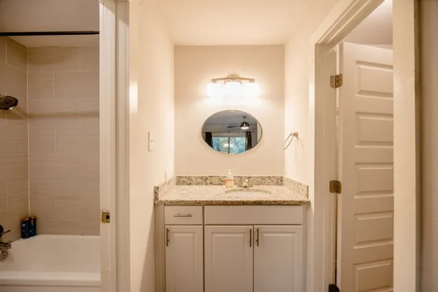 a bathroom with a granite countertop sink a mirror and shower