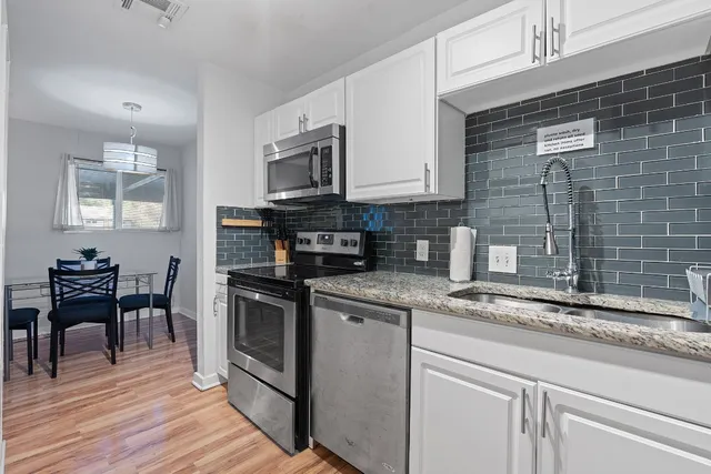 a kitchen with stainless steel appliances granite countertop a stove a sink dishwasher and a microwave oven with wooden floor