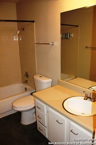 a bathroom with a granite countertop toilet sink and mirror