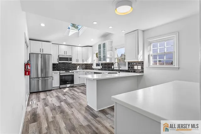 a kitchen with stainless steel appliances granite countertop a sink a stove a refrigerator counter top space and cabinets