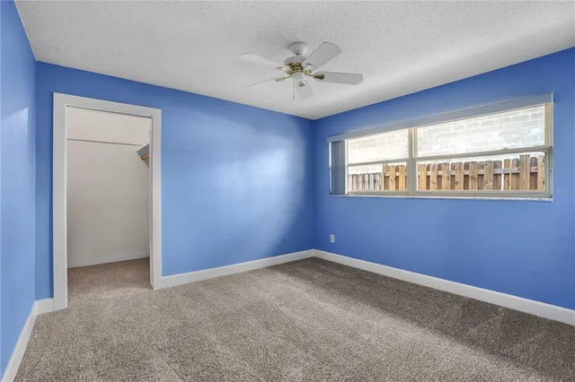 an empty room with windows and ceiling fan