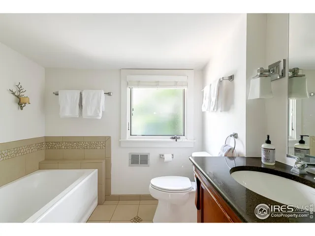 a bathroom with a granite countertop sink a toilet a mirror and bathtub