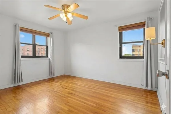 a view of empty room with wooden floor and fan